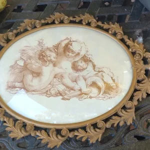 medaglione con putti in metallo dorato con vetro bombato